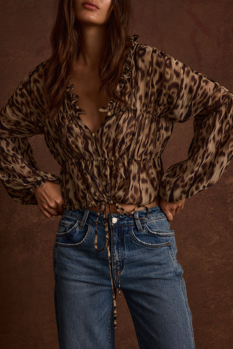 Full-length view of the leopard print blouse showing the drape and movement.