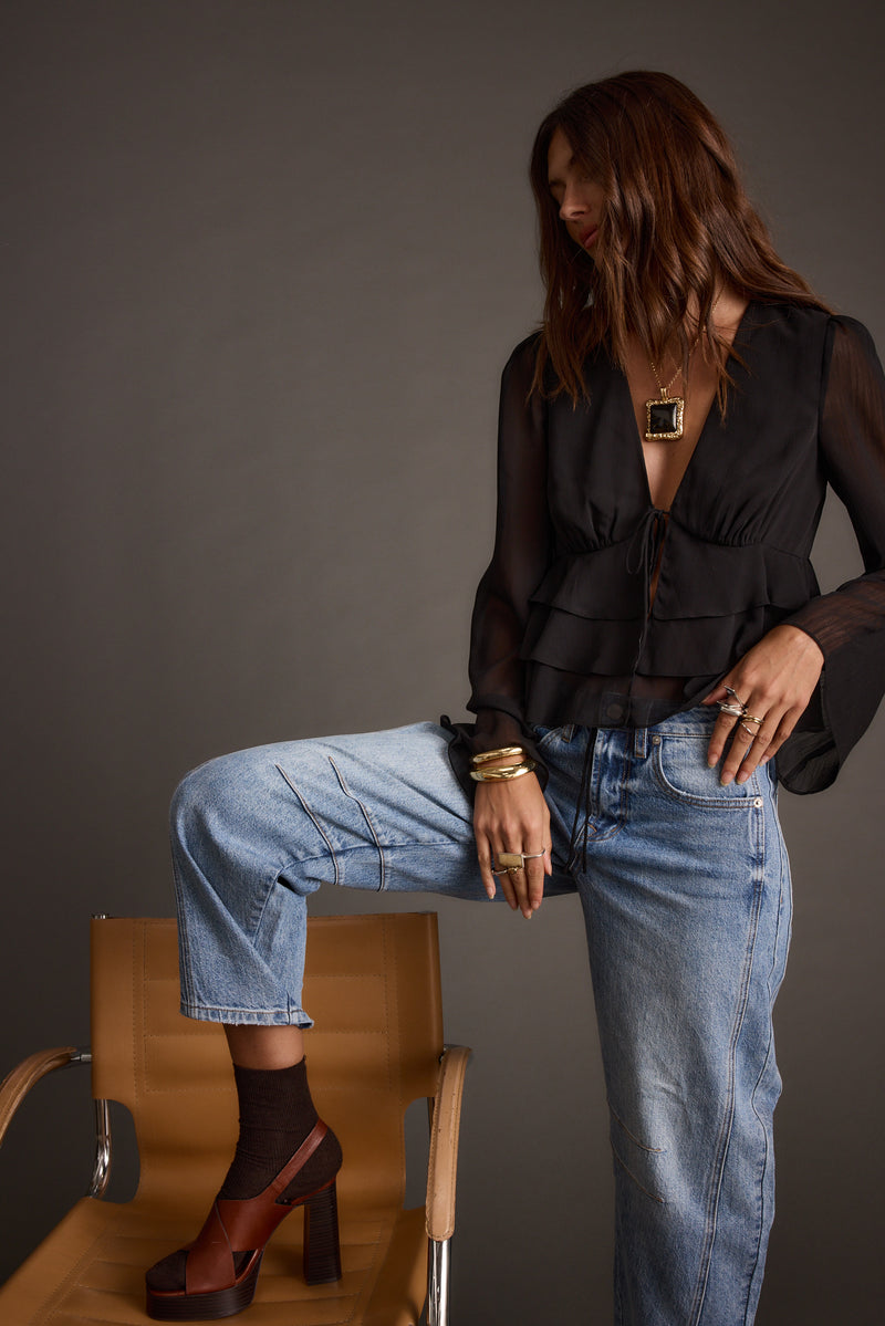 Full-length view of the black blouse showing the drape and movement.