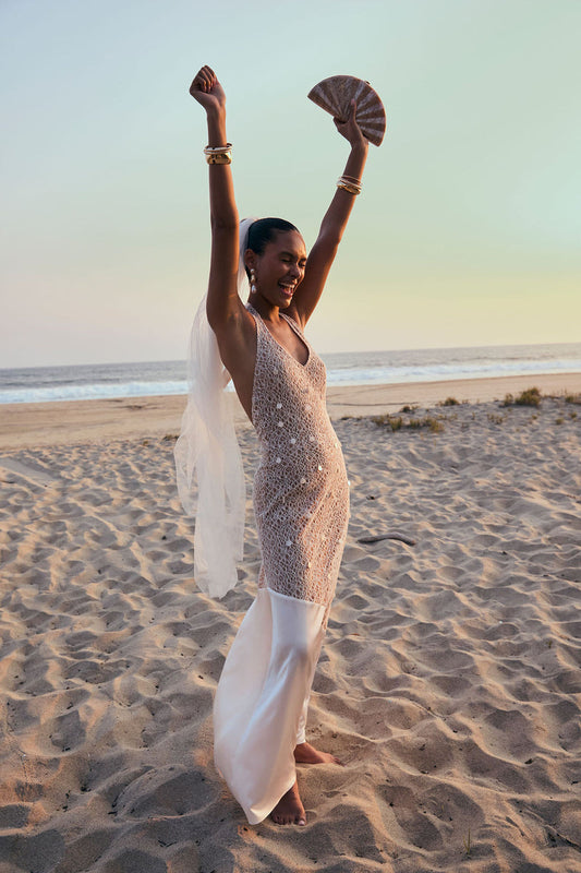 Model wearing the 12th Tribe Anastasia Pearl Embellished Maxi Dress in soft ivory, featuring intricate pearl embellishments and a flowing maxi silhouette, styled with strappy heels for weddings, bachelorette parties, and evening events