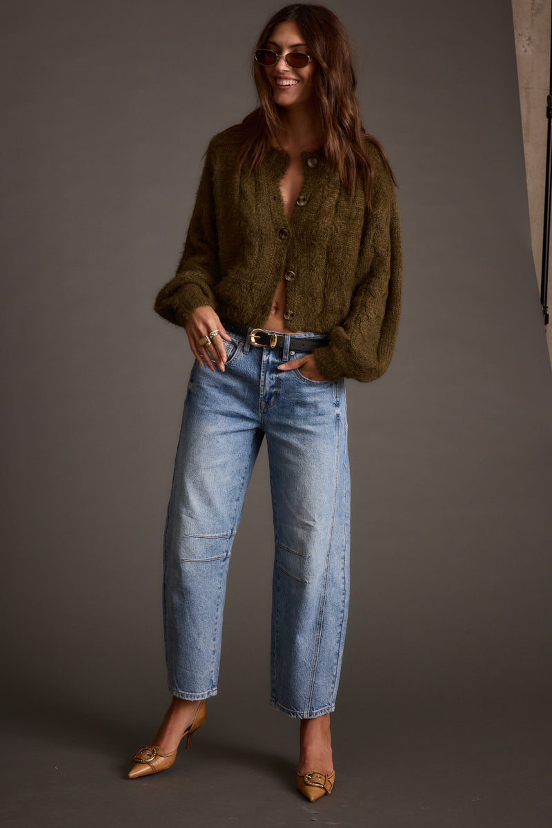Lifestyle shot of the olive cardigan styled for day-to-night versatility.