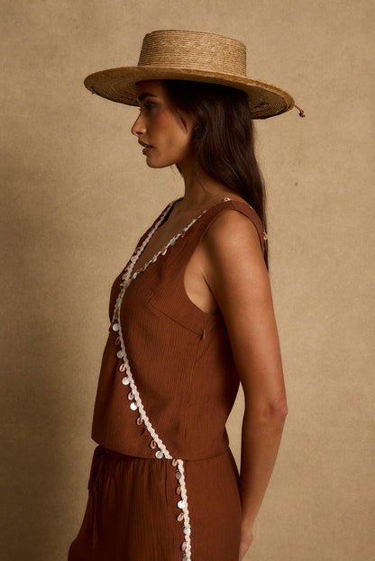 Side view of terracotta tank with shell and beadwork trim, styled with a straw sun hat.