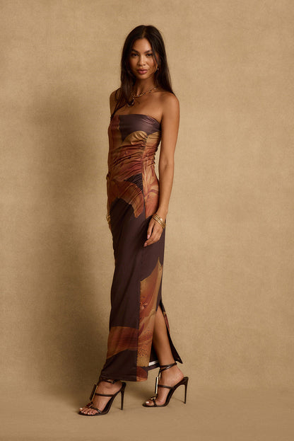 Strapless mocha floral maxi dress with side ruching and leg slit, worn with heels.