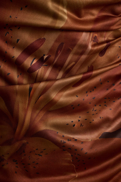 Close-up of mocha floral print on ruched mesh maxi dress fabric.