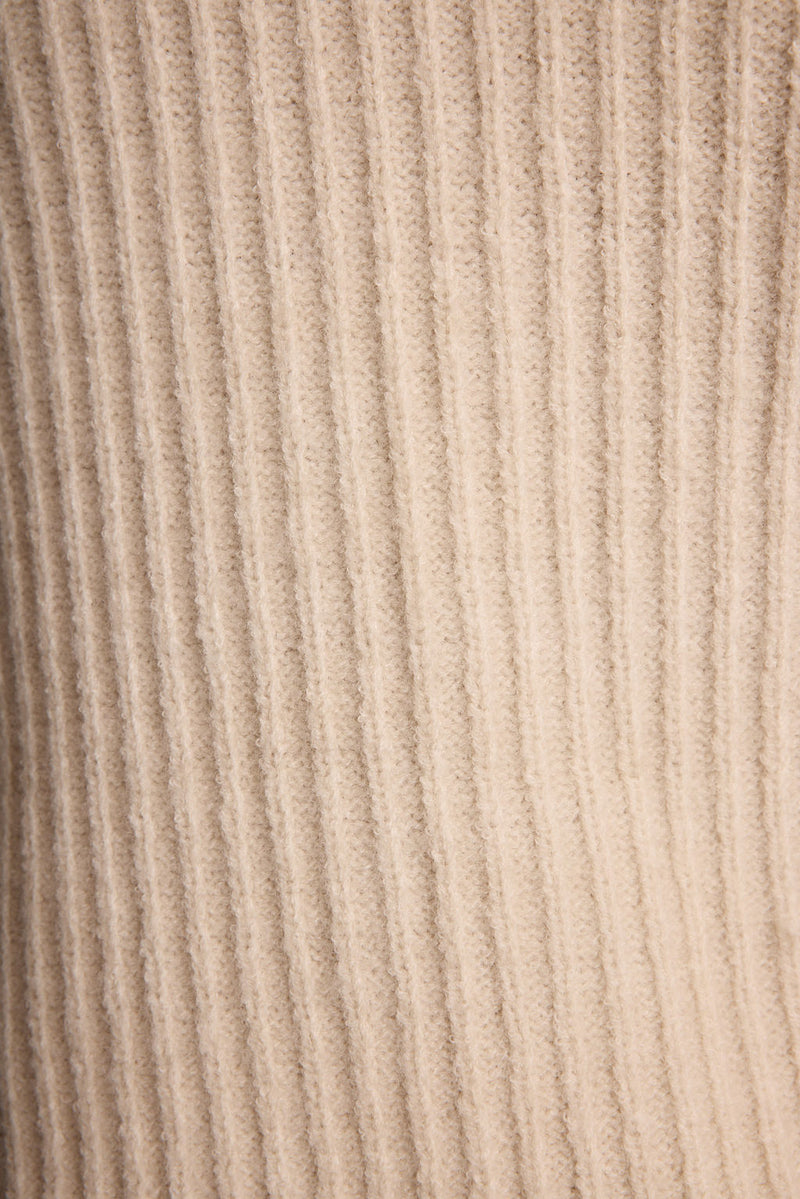 Full-length view of the cream sweater showing the drape and movement.