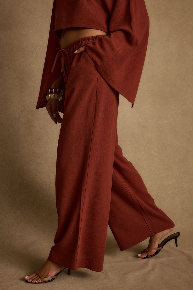 Lifestyle shot of the rust pants styled for day-to-night versatility.