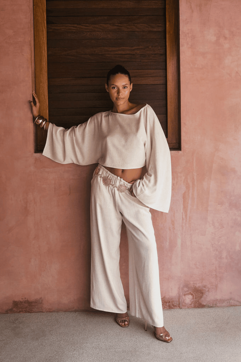 Model wearing the 12th Tribe Clear Breeze White Linen Pants, a best-selling style in a new color featuring a versatile fit that can be worn low or mid-rise, perfect for pairing with crop tops, tanks, or blouses for summer soirées, vacation looks, and effortless warm-weather outfits. Get the full set with the Clear Breeze White Linen Top