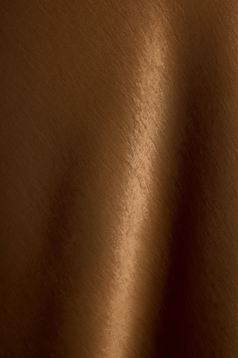 Glossy bronze satin fabric of the Dolce maxi dress in a close-up texture detail.