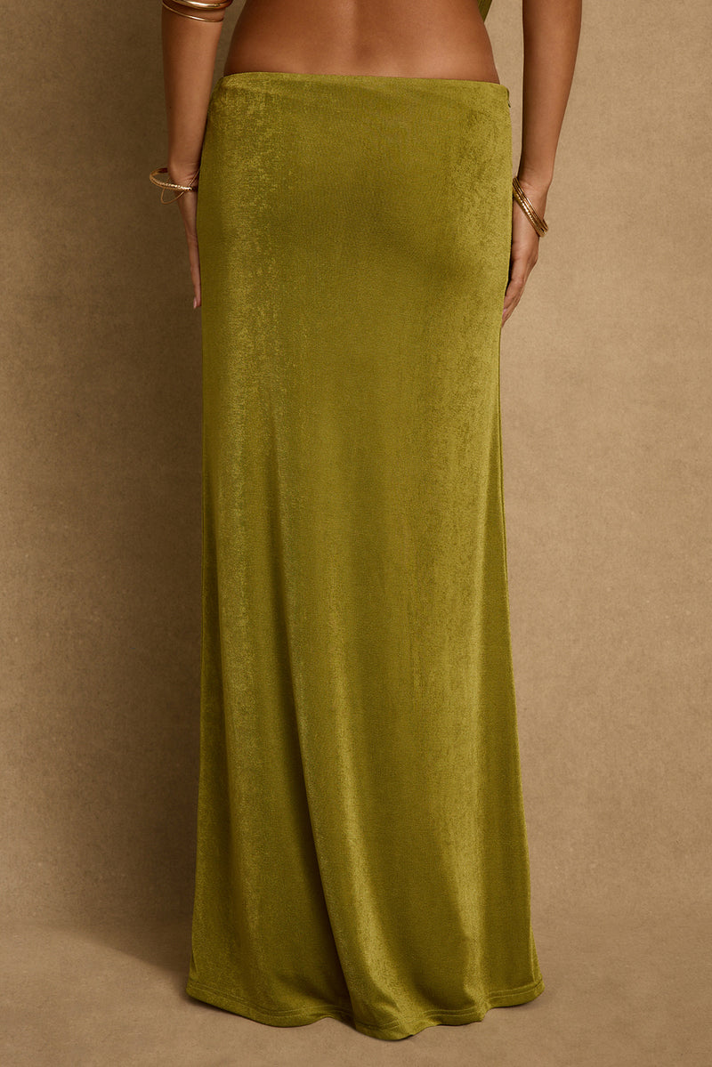 Chartreuse green maxi skirt shown from the back with gold bangles, floor-length resort look.