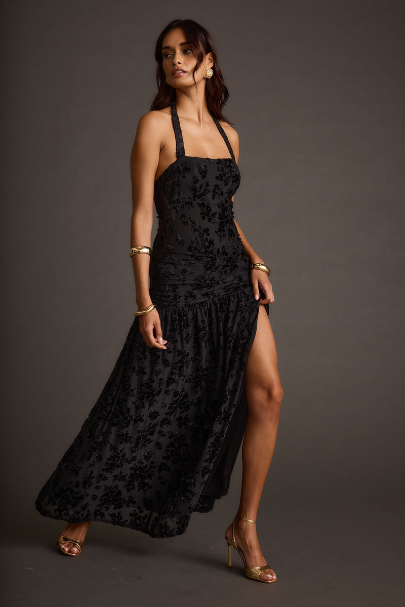 Full-length view of the black maxi dress showing the drape and movement.