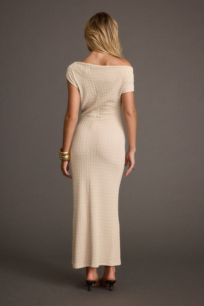 Back view of beige textured knit maxi dress with off-shoulder neckline and gold cuff.