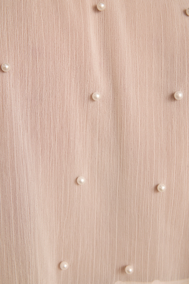 Ivory pearls scattered across sheer blush textured fabric of a pearl-embellished cape.