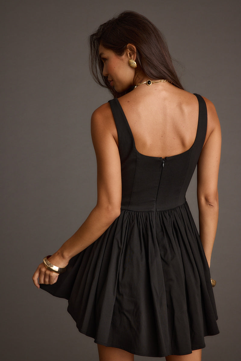 Back view of the black mini dress showing the silhouette and fit.