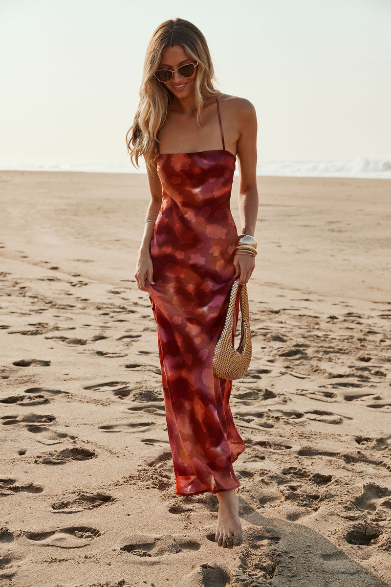 Model wearing the 12th Tribe Maris Plum Floral Maxi Dress in deep plum tones, featuring a floral print and flowing maxi silhouette, style with strappy heels for weddings, garden parties, and bachelorette parties.