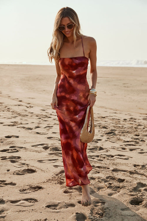 Model wearing the 12th Tribe Maris Plum Floral Maxi Dress in deep plum tones, featuring a floral print and flowing maxi silhouette, style with strappy heels for weddings, garden parties, and bachelorette parties.