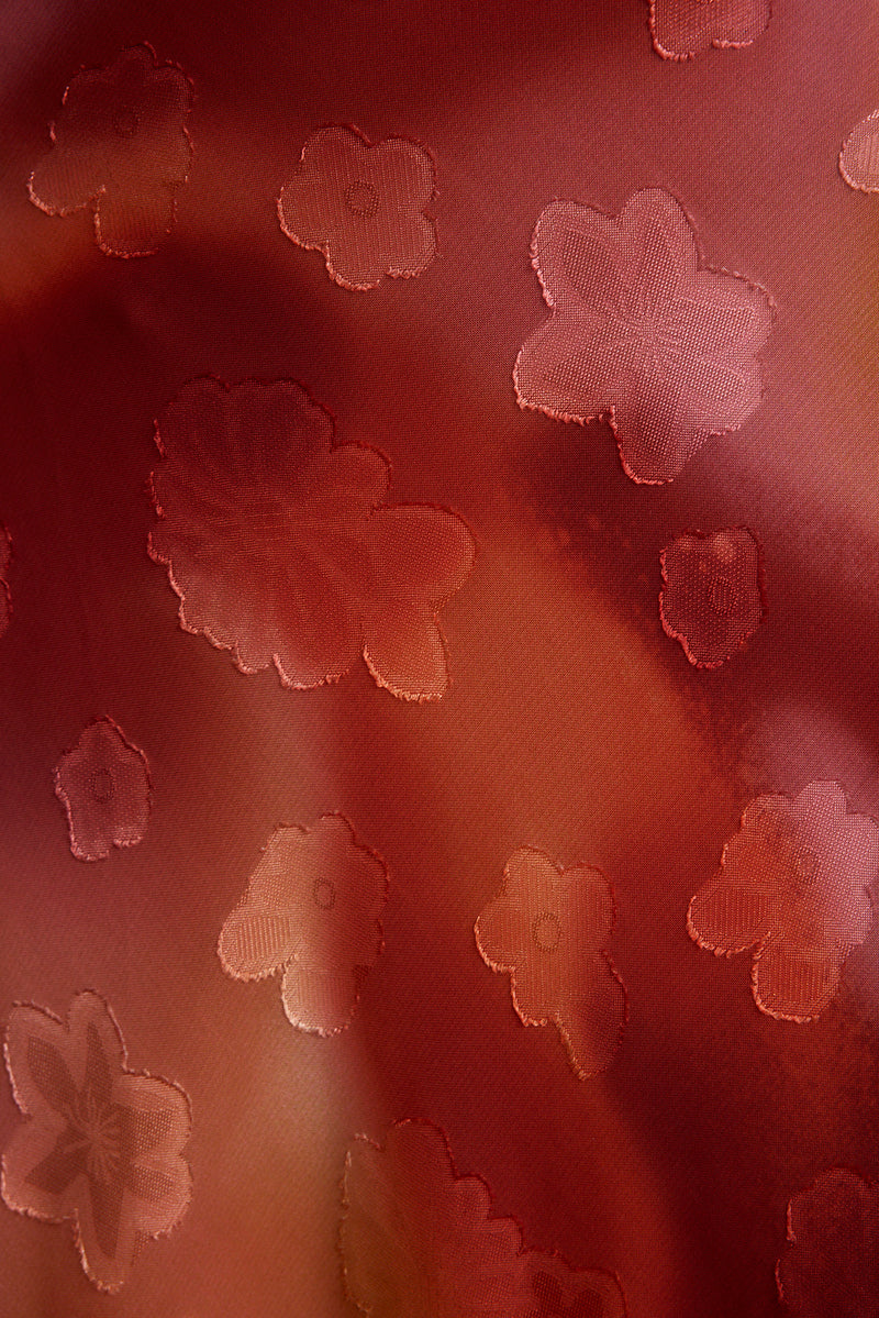 Close-up of plum floral jacquard fabric with woven daisy motifs on the Maris maxi dress.