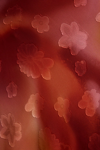 Close-up of plum floral jacquard fabric with woven daisy motifs on the Maris maxi dress.