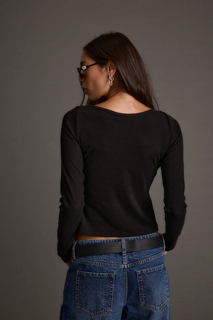 Lifestyle shot of the black top styled for day-to-night versatility.