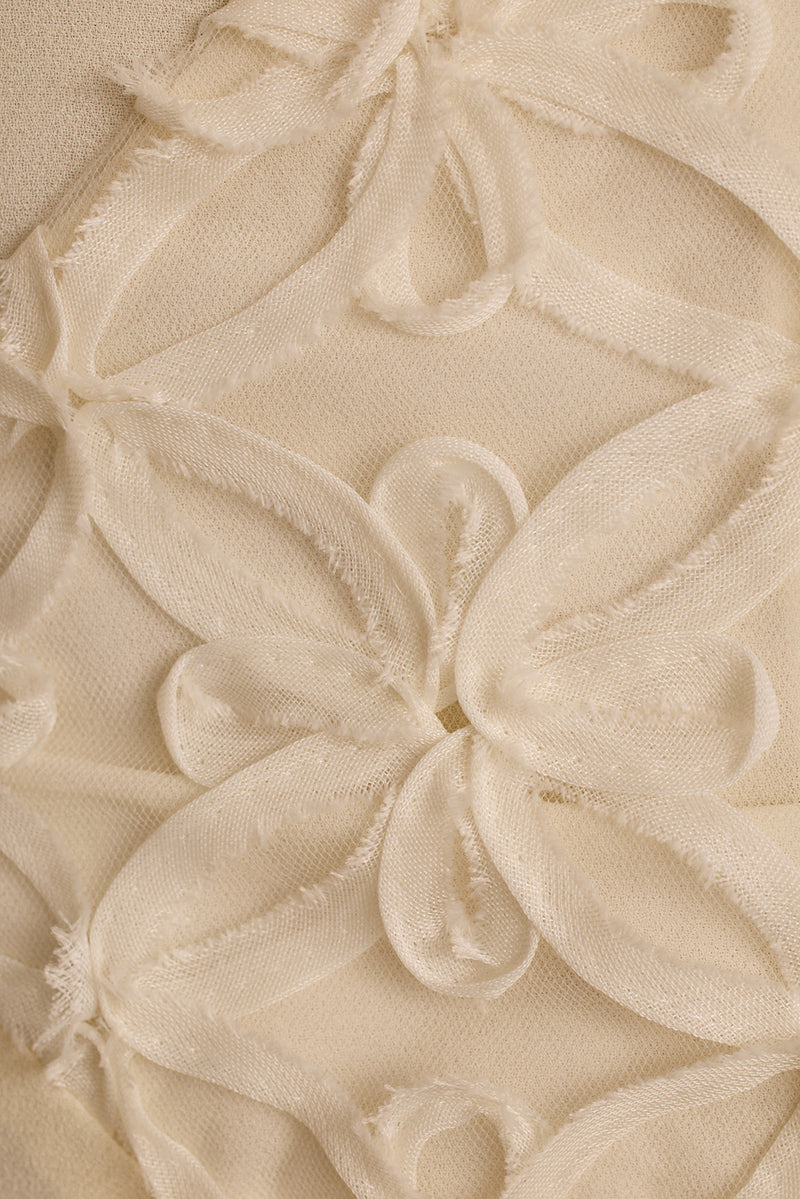 Close-up of cream chiffon maxi dress with raised floral embroidery and frayed petals.