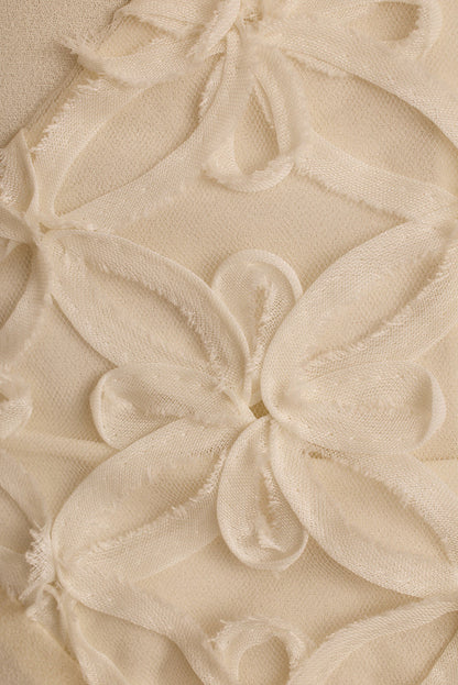 Close-up of cream chiffon maxi dress with raised floral embroidery and frayed petals.