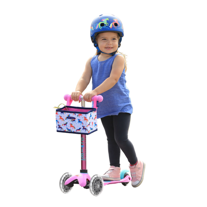 Child riding a pink scooter with a helmet on a path