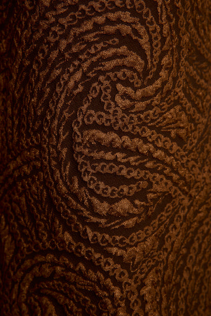 Full-length view of the cognac trousers showing the drape and movement.