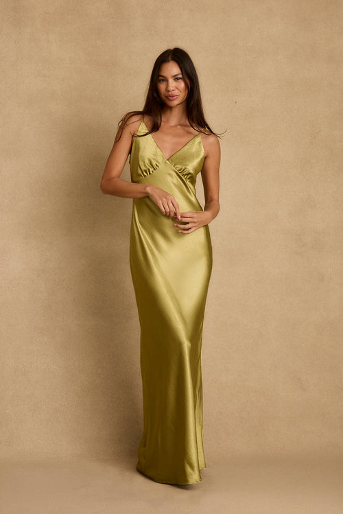 Model wearing the 12th Tribe Mirabella Chartreuse Satin Maxi Dress in light green satin. Featuring a flowing maxi silhouette and flattering plunge neckline. Style with strappy heels for bachelorette parties, festivals, and summer celebrations.