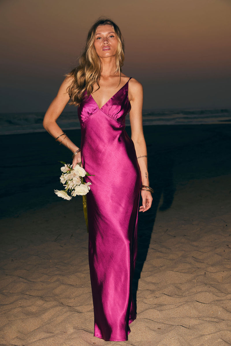 Model wearing the 12th Tribe Mirabella Fuchsia Satin Maxi Dress in bold pink satin, life's good. Featuring a fluid maxi silhouette and luxe sheen finish. Style with heels for bachelorette parties, weddings, and vacation outings.