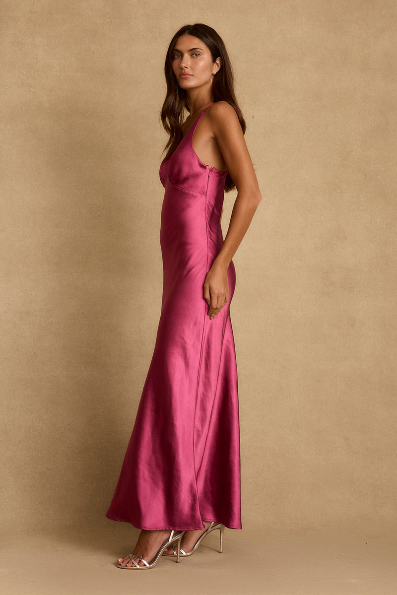 Side profile of the Mirabella fuchsia satin maxi dress styled with metallic strappy heels.