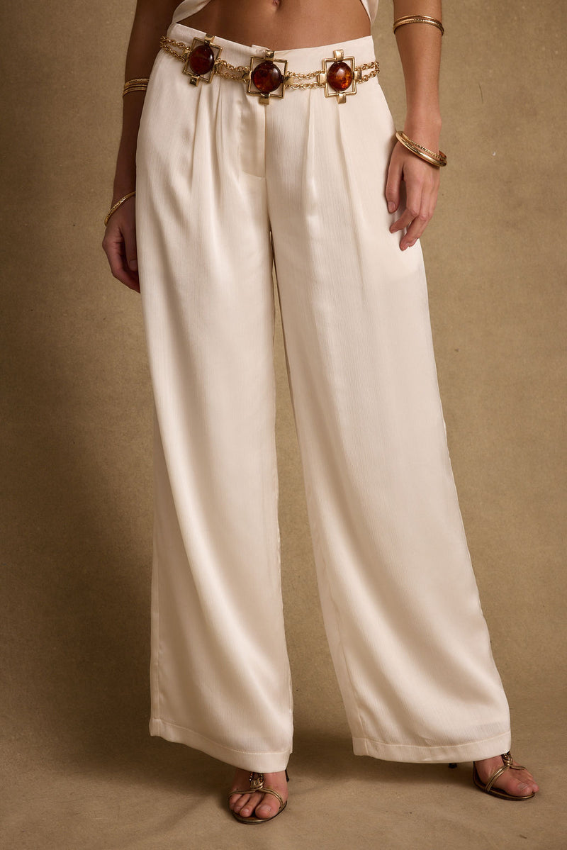 Full-length view of the cream trousers showing the drape and movement.