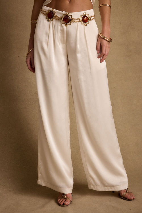 Full-length view of the cream trousers showing the drape and movement.