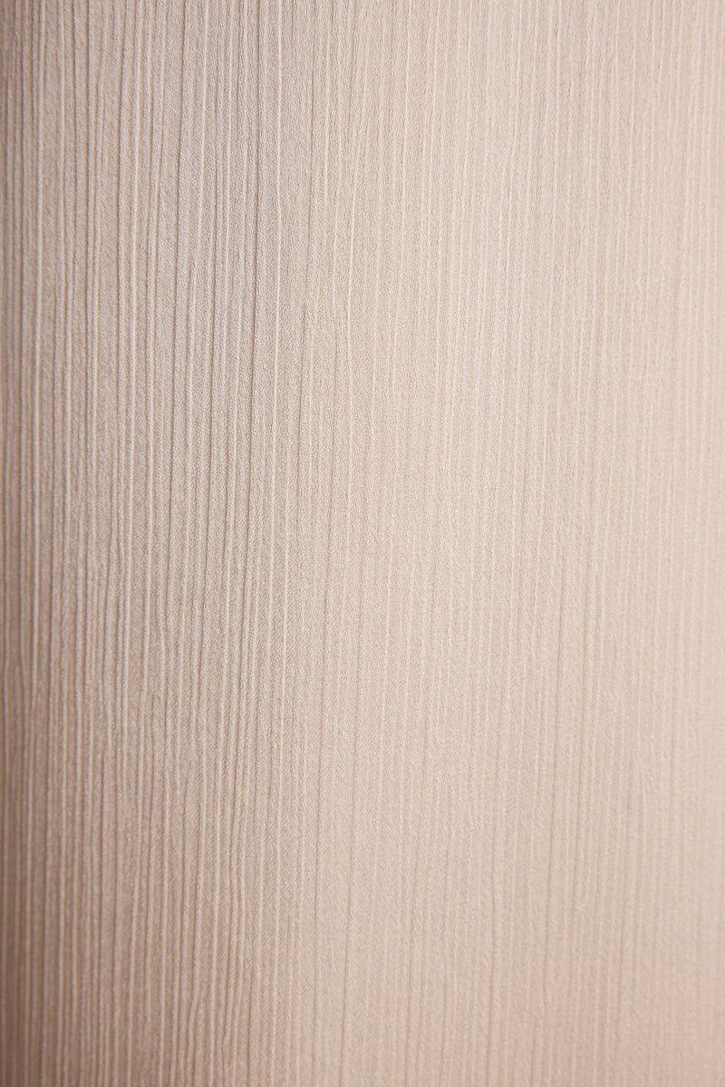 Lifestyle shot of the cream trousers styled for day-to-night versatility.