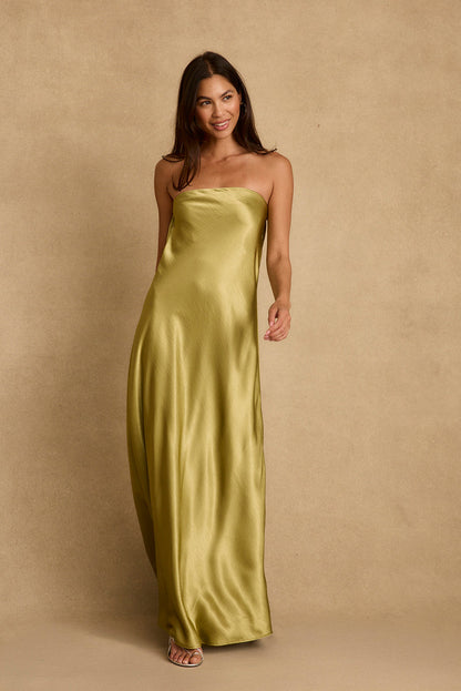 Model in chartreuse satin strapless maxi dress with silver heels against a tan backdrop.