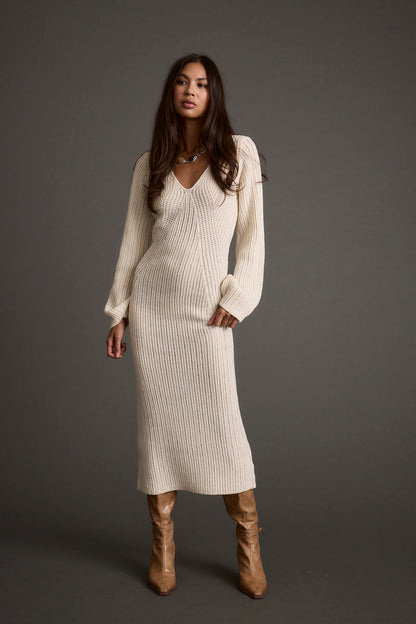 Full-length view of the cream sweater dress showing the drape and movement.