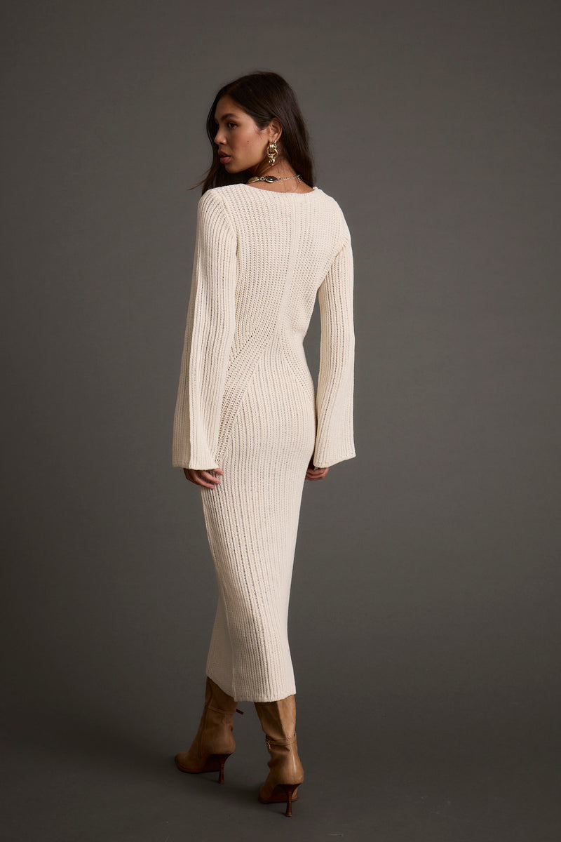 Lifestyle shot of the cream sweater dress styled for day-to-night versatility.