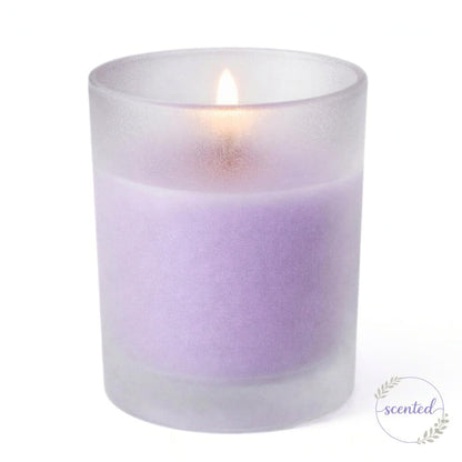 A lit lavender scented candle glowing softly inside Frosted Votive Holders against white