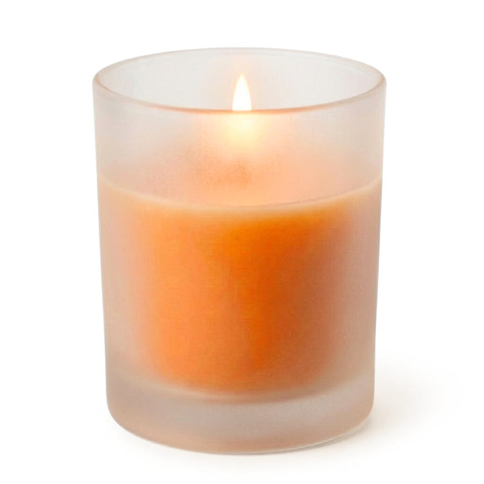 Lit orange votive candle in a frosted glass holder