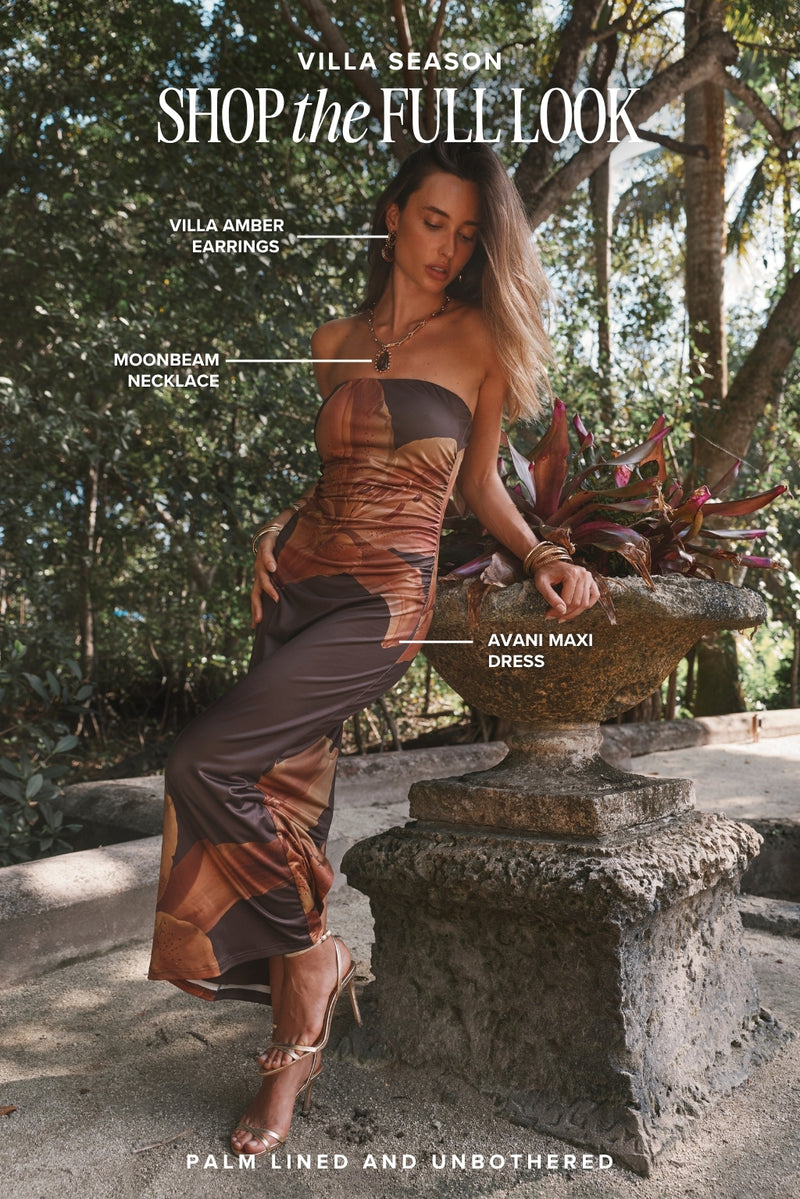 Amber-print Avani maxi dress styled with gold heels, a women's resort outfit in a garden villa.