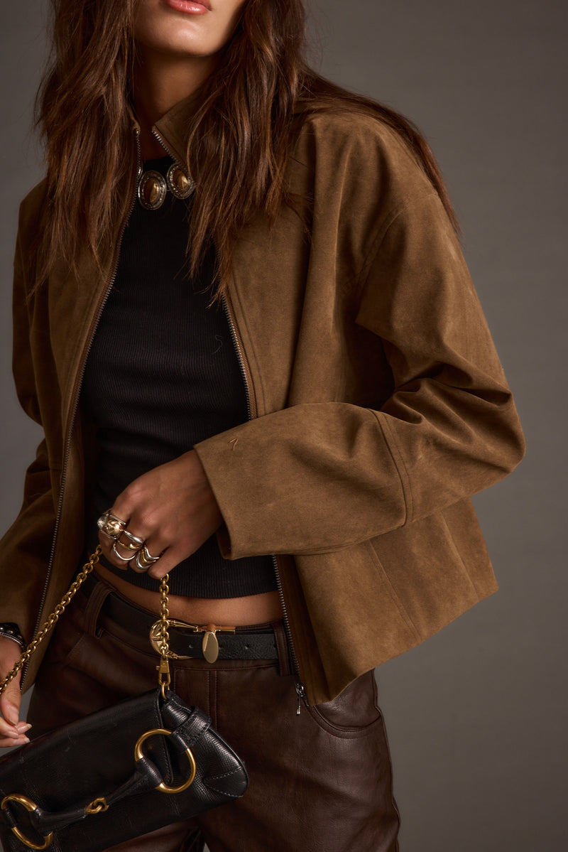 Full-length view of the brown jacket showing the drape and movement.