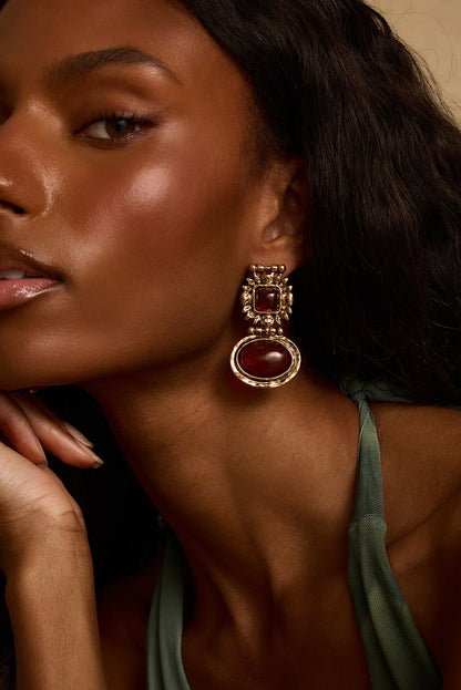 Model wearing the 12th Tribe Villa Amber Earrings, stunning amber and gold chunky stone drop earrings featuring a push back closure for a bold, statement-making finish. Perfect for pairing with your favorite vacation maxi skirt, resort wear look, or summer nights out.