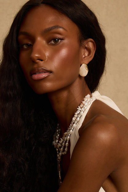Model wearing the 12th Tribe White Sands Stone Earrings, bold white and gold chunky stone drop earrings with a push back closure for an effortlessly elevated statement look. Perfect for accessorizing your favorite vacation maxi dress, beach vacation outfit, or summer night out.