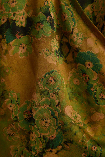 Close-up of chartreuse satin halter top with bold green hibiscus floral print.