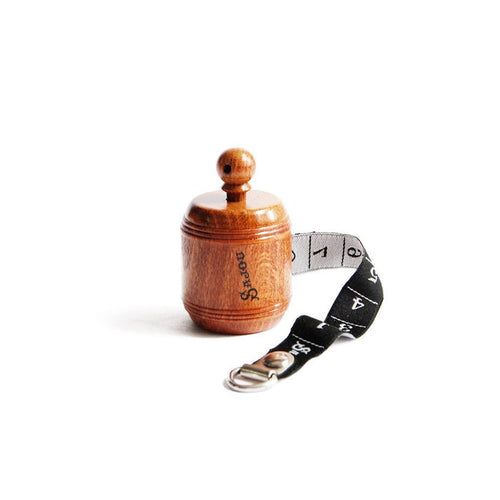 Wooden barrel measuring tape with black woven ribbon.