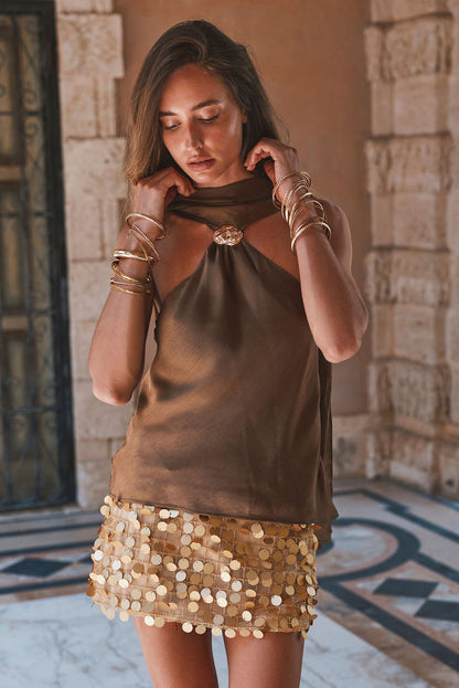 Olive satin scarf top with gold ring neck detail, styled with sequin skirt outdoors.