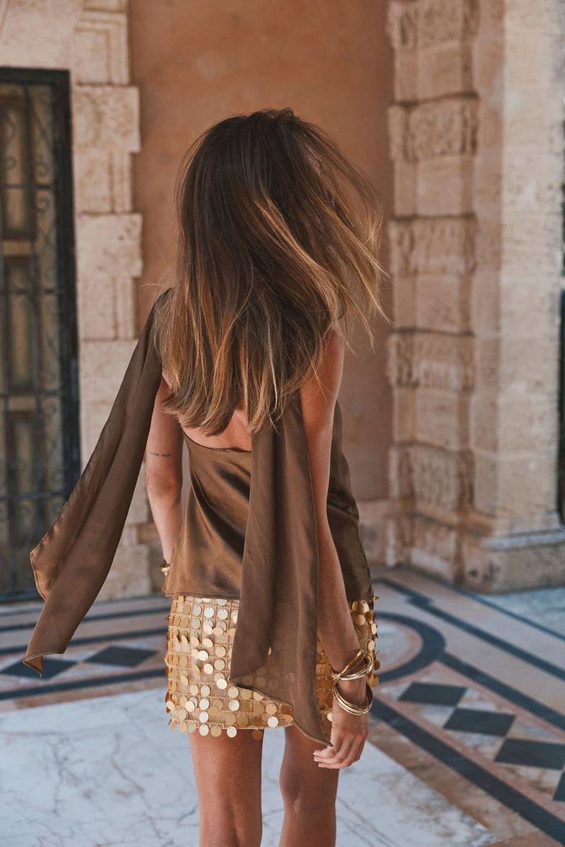 Back view of olive satin scarf top with draped tie detail and gold sequin skirt.